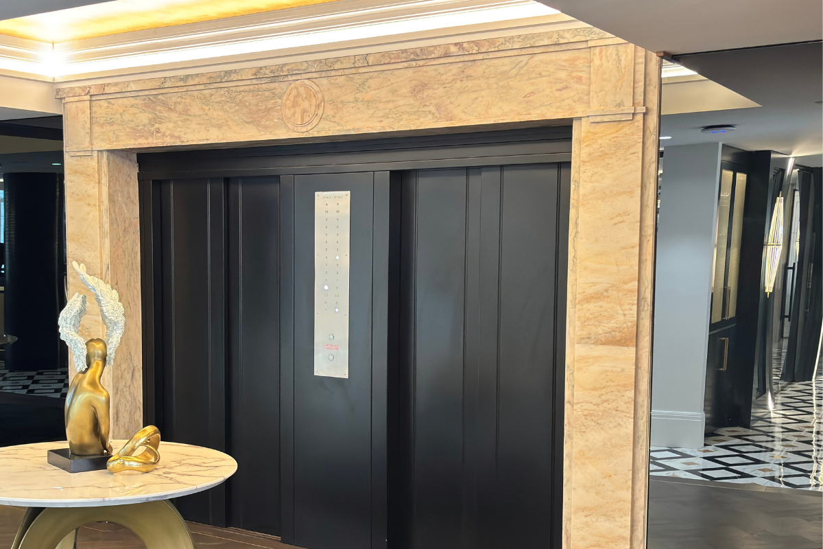 Marble-clad lift lobby with original timber lift doors