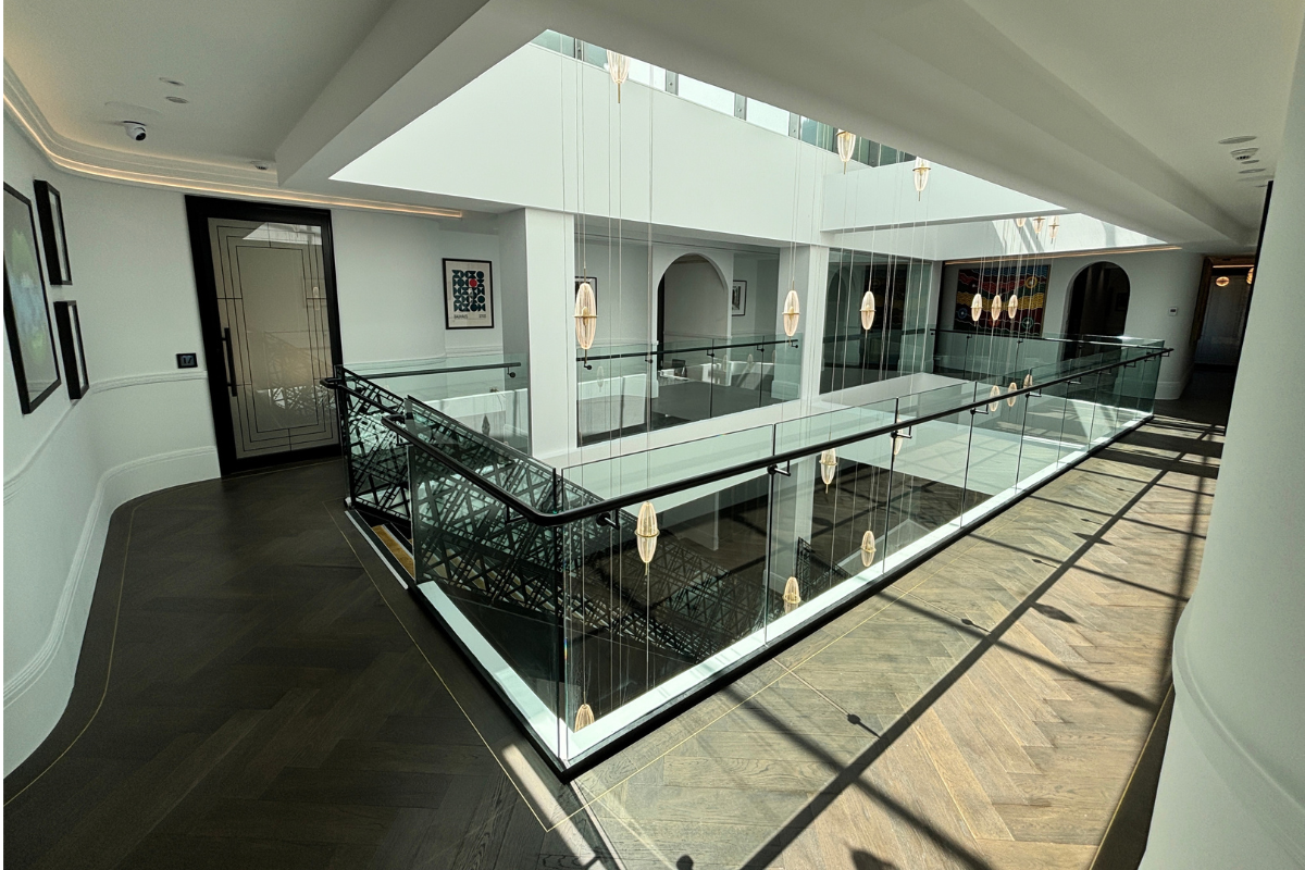 Glass-balustraded atrium void with pendant lighting and skylight